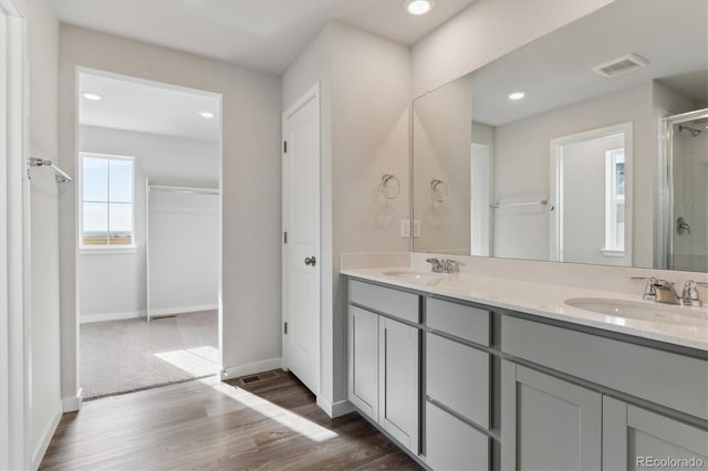 bathroom with vanity, hardwood / wood-style floors, and a shower with door