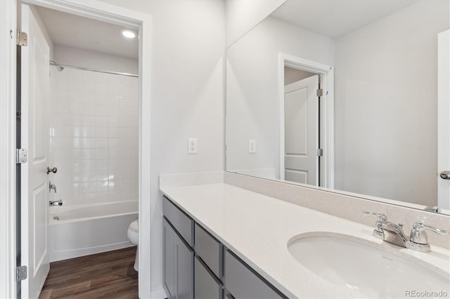 full bathroom featuring hardwood / wood-style floors, toilet, vanity, and tiled shower / bath combo