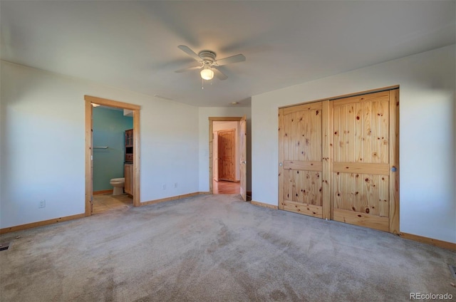 unfurnished bedroom featuring a closet, ceiling fan, light colored carpet, and ensuite bathroom