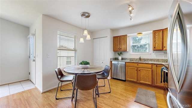 1670 S Deframe St Unit C2, Lakewood, CO 80228 - kitchen featuring appliances with stainless steel finishes, a sink, brown cabinetry, light stone countertops, and light wood-style floors