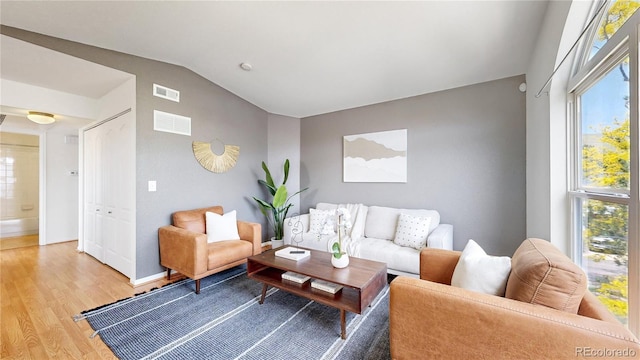 1670 S Deframe St Unit C2, Lakewood, CO 80228 - living room with light wood finished floors, lofted ceiling, healthy amount of natural light, and baseboards