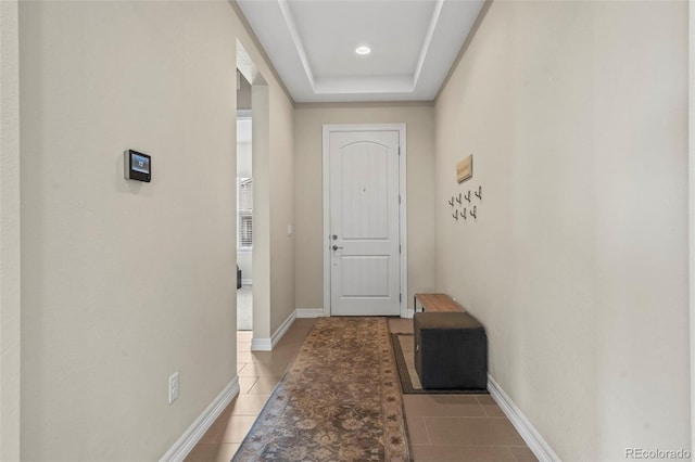 doorway to outside featuring a tray ceiling and light tile patterned floors