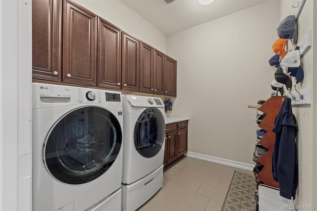 clothes washing area featuring separate washer and dryer, cabinets, and light tile patterned flooring