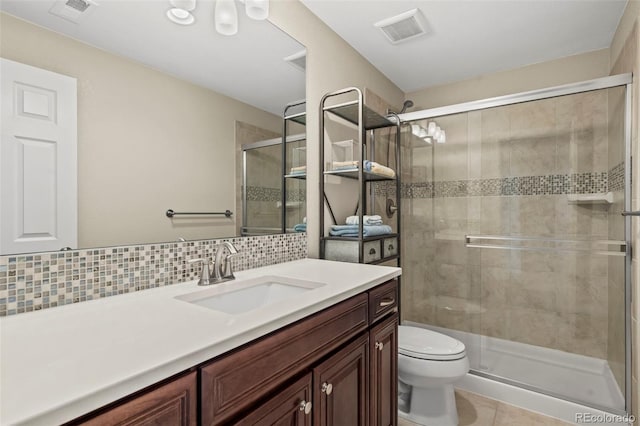 bathroom featuring toilet, a shower with door, tile patterned floors, backsplash, and vanity