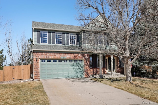 traditional-style home featuring brick siding, a shingled roof, fence, concrete driveway, and a front lawn