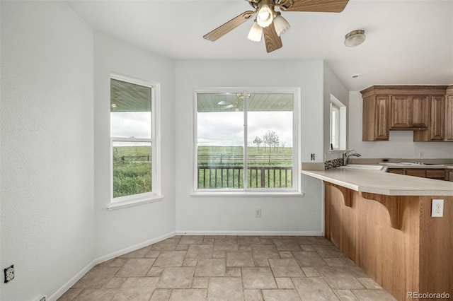 27190 Private Road 139, Agate, CO 80101 - kitchen with light stone finish floors, light countertops, brown cabinetry, a kitchen bar, and ceiling fan