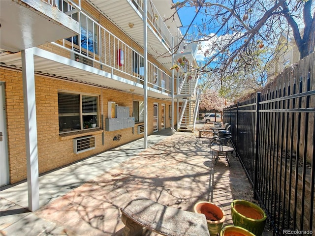 view of patio / terrace featuring fence and stairway