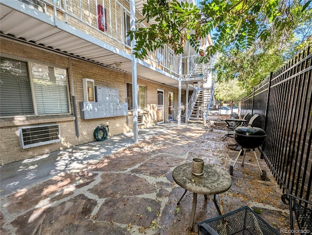view of patio / terrace featuring mail area, fence, and stairway