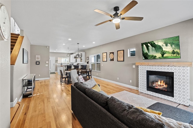 living room with light wood-type flooring, a fireplace, and baseboards