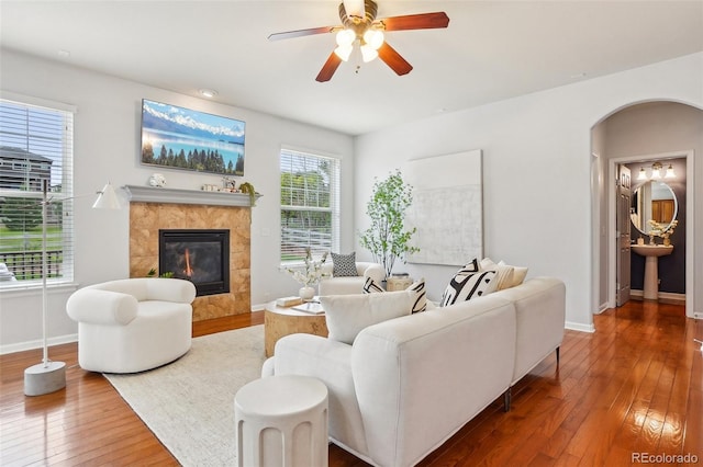 2605 Gray Wolf Loop, Broomfield, CO 80023 - living room featuring hardwood / wood-style floors, baseboards, arched walkways, a tile fireplace, and ceiling fan