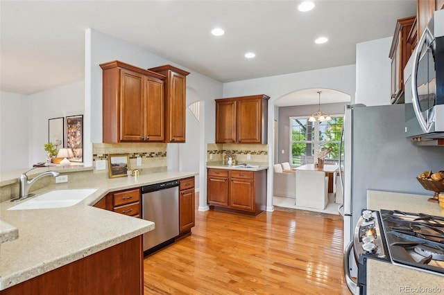 2605 Gray Wolf Loop, Broomfield, CO 80023 - kitchen featuring stainless steel appliances, a sink, arched walkways, light wood-style floors, and backsplash