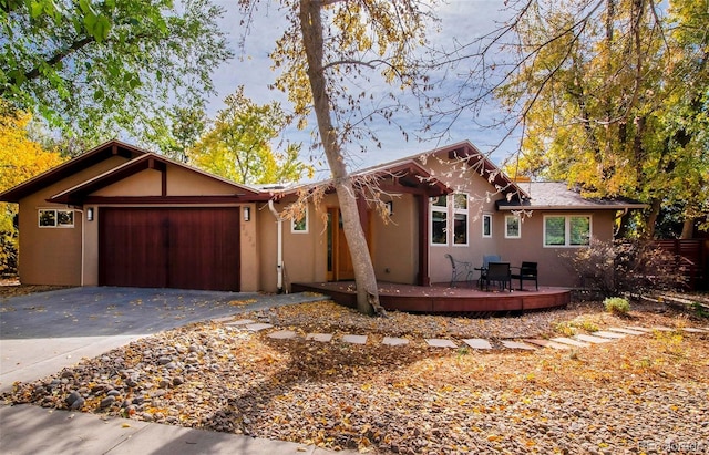 view of front of home with a garage, driveway, a deck, and stucco siding