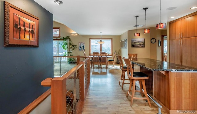 interior space featuring pendant lighting, light wood-style floors, brown cabinetry, and a kitchen breakfast bar