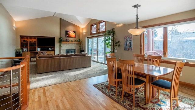 dining area with lofted ceiling, light wood-style flooring, and a tile fireplace