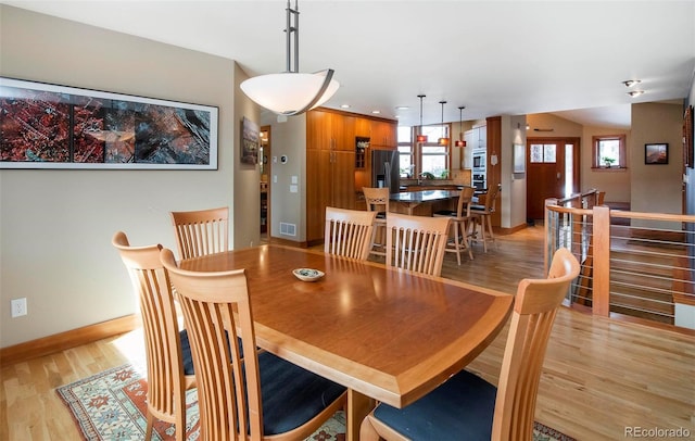 dining space with light wood finished floors, visible vents, and baseboards