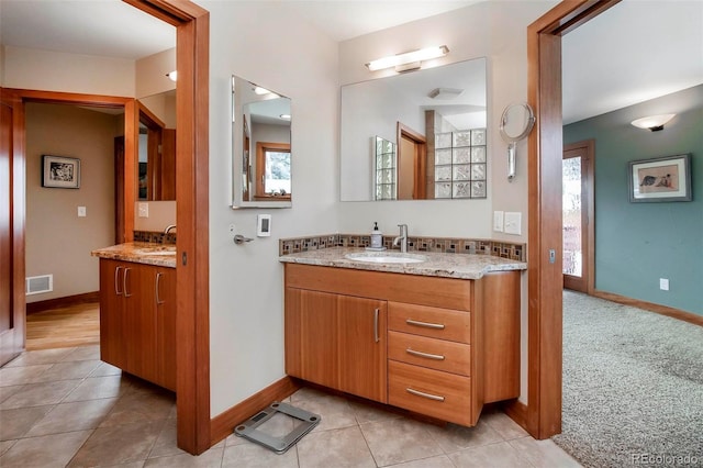 bathroom featuring two vanities, a sink, and baseboards