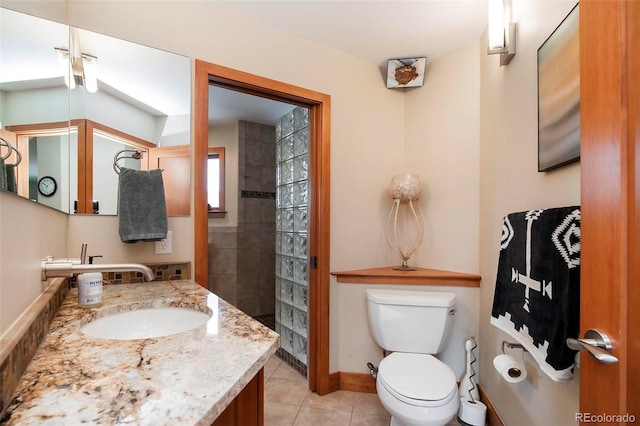 full bath featuring toilet, vanity, tiled shower, baseboards, and tile patterned floors