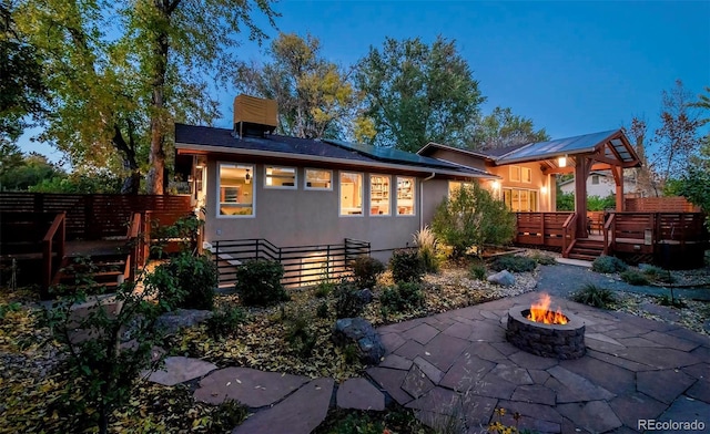 rear view of house featuring stucco siding, a patio area, fence, a deck, and a fire pit