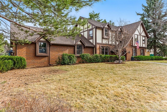 tudor-style house with brick siding, stucco siding, and a front lawn