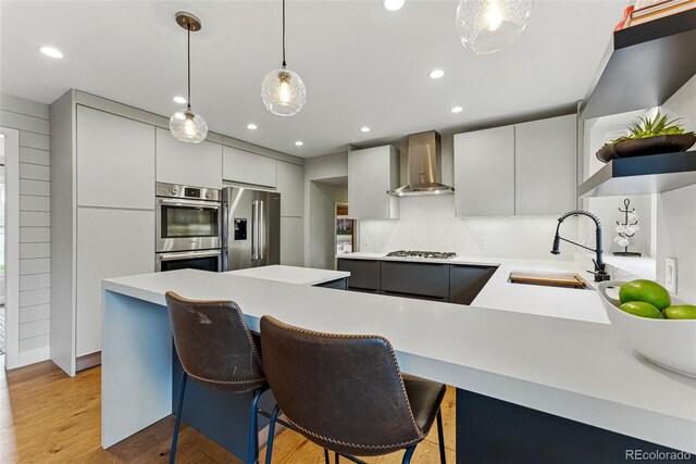 kitchen featuring a sink, wall chimney exhaust hood, modern cabinets, and stainless steel appliances