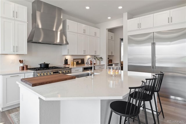 3147 S Quaker St, Morrison, CO 80465 - kitchen with wall chimney range hood, stainless steel built in refrigerator, light wood-style flooring, recessed lighting, and stove