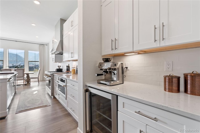 3147 S Quaker St, Morrison, CO 80465 - kitchen featuring wine cooler, white cabinets, decorative backsplash, wall chimney exhaust hood, and light wood finished floors