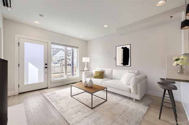 living area featuring recessed lighting, baseboards, and light wood finished floors