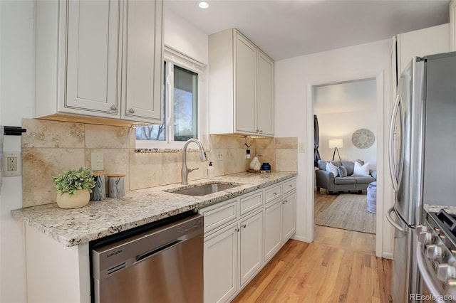 kitchen with white cabinets, appliances with stainless steel finishes, light hardwood / wood-style flooring, and sink