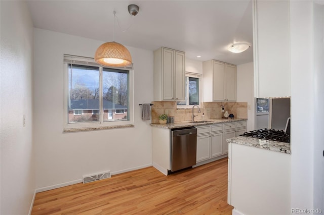 kitchen with stainless steel appliances, sink, light hardwood / wood-style flooring, white cabinets, and hanging light fixtures