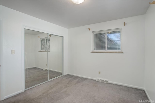 unfurnished bedroom featuring light carpet and a closet