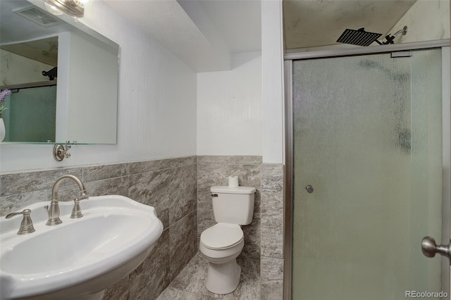 bathroom featuring walk in shower, sink, tile walls, tile patterned flooring, and toilet