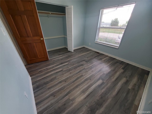 unfurnished bedroom with a closet and dark wood-type flooring