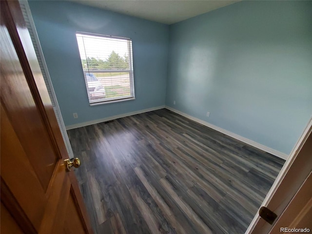 unfurnished room featuring dark wood-type flooring and baseboards