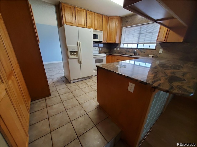 kitchen featuring white appliances, a peninsula, backsplash, and light tile patterned flooring
