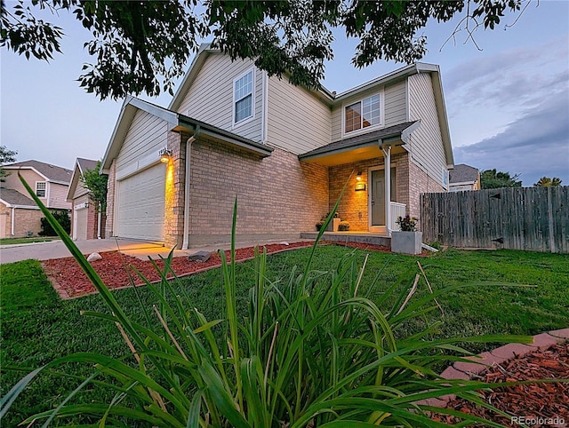 view of front of property featuring concrete driveway, a front lawn, an attached garage, fence, and brick siding
