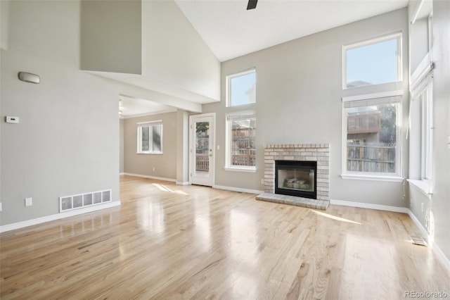 unfurnished living room with a towering ceiling, baseboards, visible vents, and a fireplace