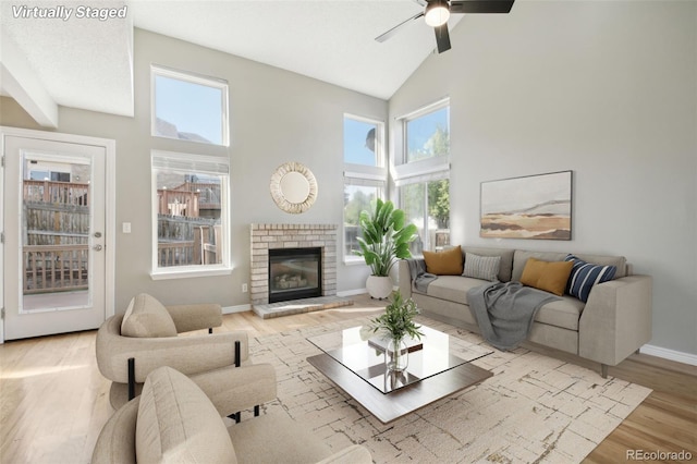 living area with light wood-style floors, baseboards, a ceiling fan, and high vaulted ceiling