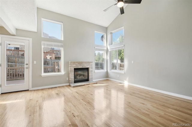 unfurnished living room with high vaulted ceiling, a ceiling fan, wood finished floors, and a healthy amount of sunlight