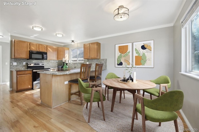 kitchen with tasteful backsplash, black microwave, stainless steel range with electric stovetop, and light wood-type flooring