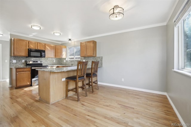 kitchen with backsplash, black microwave, a healthy amount of sunlight, and stainless steel electric range oven