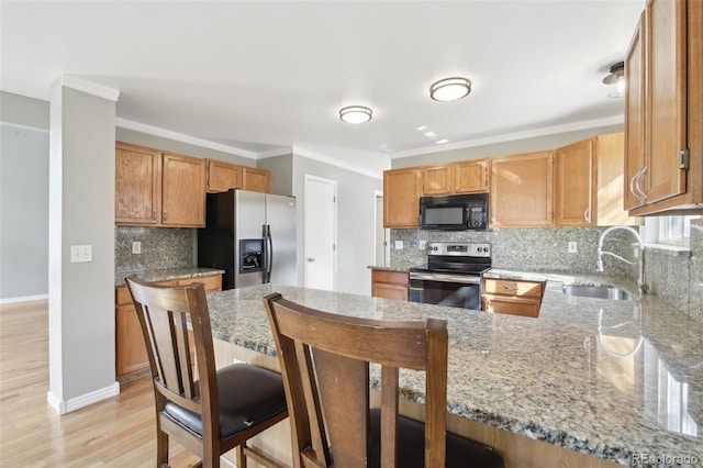 kitchen featuring stainless steel appliances, a sink, light stone countertops, a peninsula, and tasteful backsplash