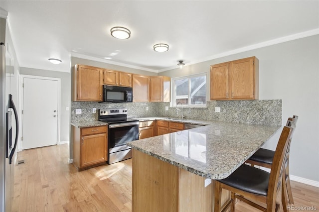 kitchen featuring stainless steel appliances, a peninsula, decorative backsplash, and a kitchen bar
