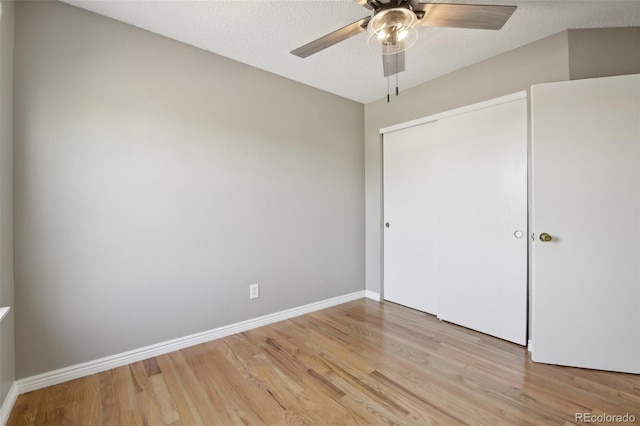 unfurnished bedroom with light wood finished floors, a ceiling fan, baseboards, and a closet