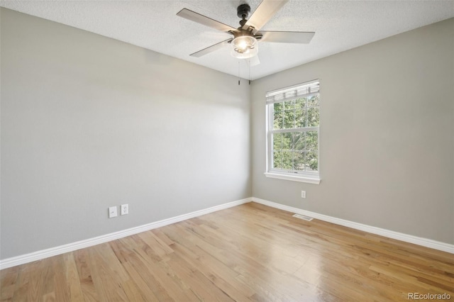 unfurnished room featuring light wood-type flooring, visible vents, a ceiling fan, and baseboards