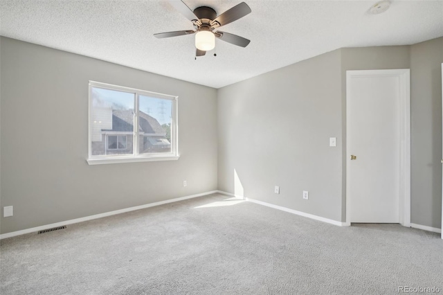 empty room with carpet floors, visible vents, baseboards, and ceiling fan