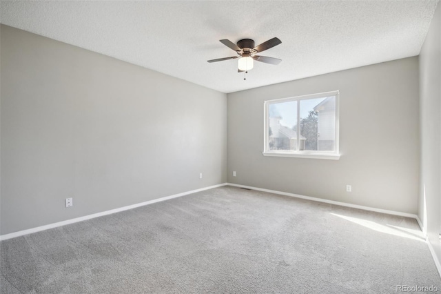 empty room with ceiling fan, baseboards, carpet flooring, and a textured ceiling