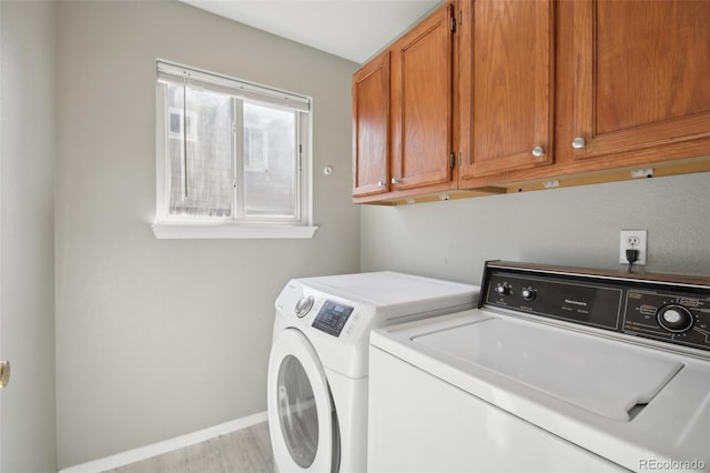 laundry room with cabinet space, wood finished floors, baseboards, and washer and clothes dryer