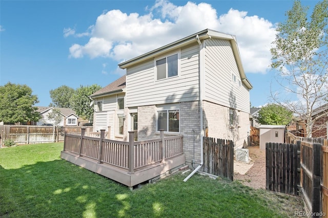 back of house with a fenced backyard, brick siding, a deck, and a yard