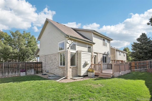 back of property featuring brick siding, a lawn, a fenced backyard, and a deck