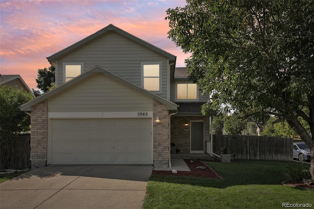 traditional home with driveway, fence, a garage, brick siding, and a lawn
